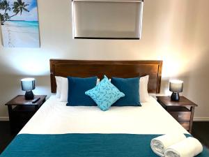 a bedroom with a bed with blue and white pillows at City Ville Apartments and Motel in Rockhampton