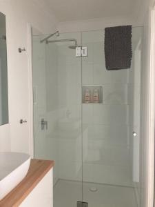 a glass shower in a bathroom with a sink at Rosewhite House in Myrtleford