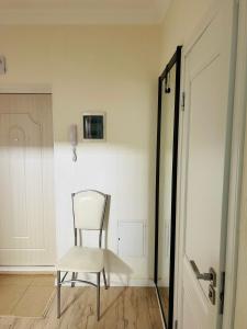 een witte stoel in een kamer naast een deur bij Уютная квартира в центре столицы in Taldykolʼ