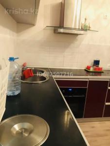 een keuken met een zwart aanrecht met een wastafel bij Уютная квартира в центре столицы in Taldykolʼ