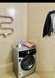 een wasmachine en droger in de badkamer bij Уютная квартира в центре столицы in Taldykolʼ