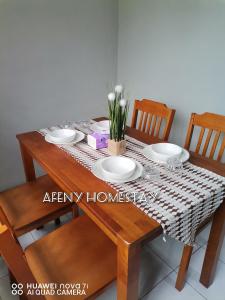 - une table à manger avec des assiettes et des fleurs dans l'établissement Afeny Homestay, à Tawau