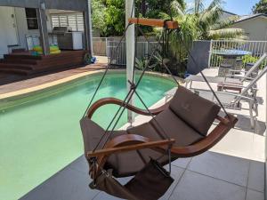 a swinging chair sitting next to a swimming pool at Luxury oasis resort Pet friendly apartment with private pool and spa in Port Macquarie
