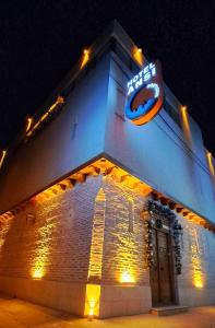 a building with a neon sign on it at night at Hotel Ansi Boutique W&S terrace in Bukhara