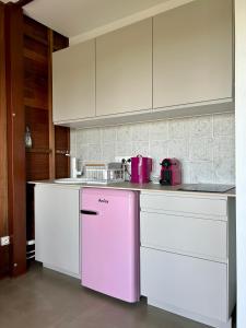cocina con nevera rosa y armarios blancos en Ti Kaz C2C - Une maison Balinaise, en Saint-Pierre