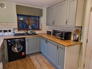 cocina con armarios azules y lavavajillas en Purdie Close Holiday Let, en Cheddar