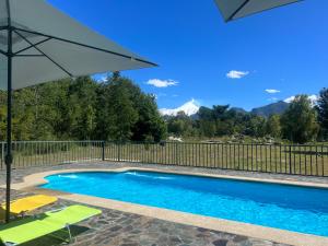 a swimming pool with chairs and an umbrella at Rümü in Pucón