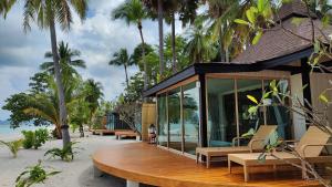 穆島的住宿－穆島西拉威海灘度假酒店，海滩上的房子,长椅和棕榈树