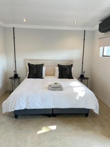 a bedroom with a large white bed with two tables at Lighthouse Guesthouse & Cafe in Groblersdal