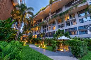 um edifício de apartamentos com um guarda-sol e um jardim em HOMA Phuket Town em Cidade Phuket