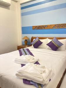 1 dormitorio con cama con sábanas blancas y almohadas moradas en Wiriya House en Chiang Mai