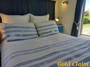 a bed with a blue and white comforter and a window at Charleston Goldfields Accommodation in Charleston