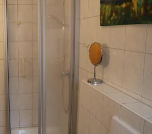 um chuveiro com um espelho numa prateleira na casa de banho em Ferienhaus Inselblick em Dornumersiel