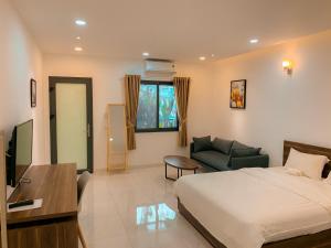 a bedroom with a bed and a couch and a television at DOME APARTMENT in Nhơn Trạch