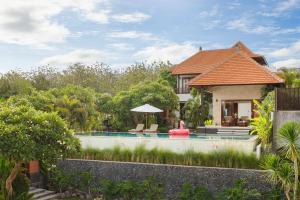 een villa met een zwembad en een huis bij The Bija Villas by Nakula in Canggu