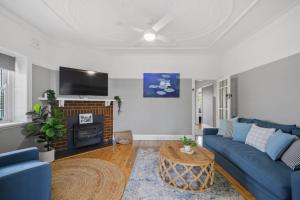 a living room with a blue couch and a tv at Bluestone Cottage - Character & Class in Orange