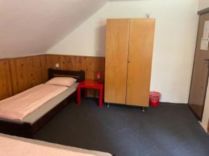 1 dormitorio con 1 cama, armario y mesa roja en Chata Barbora, en Lučany nad Nisou