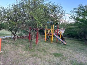 un parque infantil en un campo con un árbol en INTI naile en Villa Carlos Paz