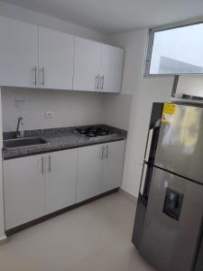 eine Küche mit weißen Schränken und einem Kühlschrank aus Edelstahl in der Unterkunft Apartamento Hogar fuera de casa in Armenia