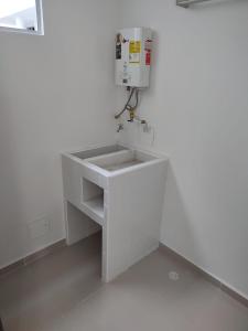 ein weißes Waschbecken in einem weißen Zimmer mit einer Kaffeemaschine in der Unterkunft Apartamento Hogar fuera de casa in Armenia