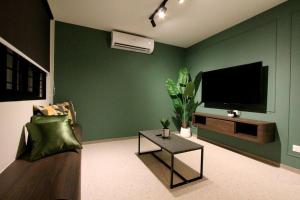 a living room with a flat screen tv on a green wall at KonZept House for 14pax #5minwalk Jonker@Heritage in Melaka