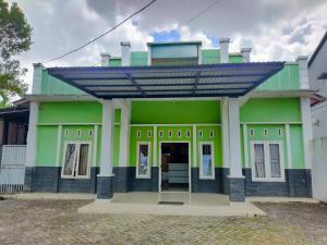 a green house with a roof on top of it at OYO 93443 Emmy Homestay Syariah in Mamuju