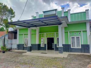 a green house with a solar roof at OYO 93443 Emmy Homestay Syariah in Mamuju