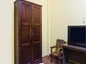 un grande armadio in legno in una camera con TV di OYO 93443 Emmy Homestay Syariah a Mamuju