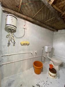 a bathroom with a toilet and a bucket at Adhya Home Stay Hampi in New Hampi
