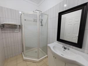 a bathroom with a shower and a sink and a mirror at Vacation Home with Lake view in Kampala