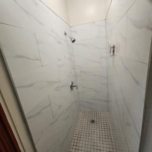 a bathroom with a shower with white tiles at New York City Guest House 2 in New York