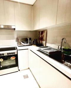 a kitchen with white cabinets and a stove and a sink at Yas Island canal 1- Formula 1, Entertainment, and Luxury Living! in Abu Dhabi