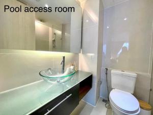 a bathroom with a glass sink and a toilet at Grande Caribbean Condo Resort by PTN in Pattaya South