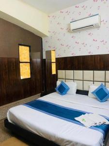 een slaapkamer met een groot bed met blauwe kussens bij Hotel Mannat International at Paschim Vihar in New Delhi