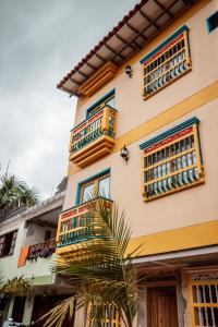 a building with balconies and a palm tree in front of it at Las Palmas Apartamentos Guatapé in Guatapé