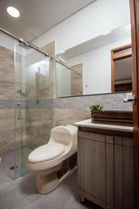 a bathroom with a toilet and a glass shower at Las Palmas Apartamentos Guatapé in Guatapé