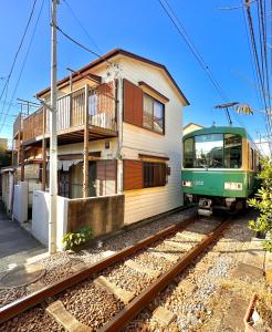 鎌倉市にある江ノ電の線路沿いにある宿【film koshigoe】の緑の列車が建物の前に停まっている
