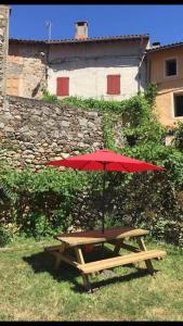 - une table de pique-nique avec un parasol rouge dans l'herbe dans l'établissement Maison&jardin charmant&typique au cœur du Conflent, à Sahorre