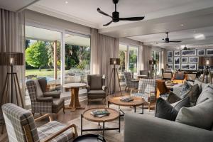 uma sala de estar com sofás, mesas e janelas em Protea Hotel by Marriott George King George em George