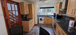 a kitchen with wooden cabinets and a washer and dryer at Grafton House in Martlesham