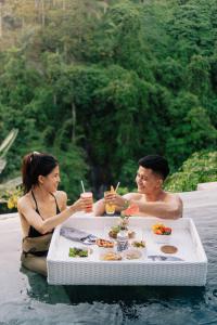 a man and woman sitting at a table in the water at Magical Jungle Resort in Ubud