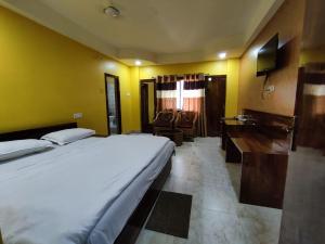 een hotelkamer met een groot bed en een bureau bij New Hindusthan Hotel in Siliguri