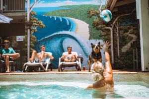 a group of people and a dog in a swimming pool at Noosa Flashpackers in Sunshine Beach