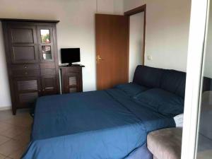 1 dormitorio con 1 cama azul y TV en House Serapide Airport en Melito di Napoli