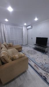 uma sala de estar com um sofá e uma televisão de ecrã plano em Двухкомнатная в 4 микрорайоне em Oral