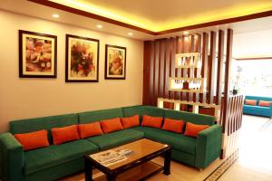 a living room with a green couch and orange pillows at Hotel Eco Tree Pokhara in Pokhara