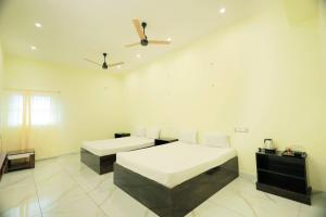 a white room with two beds and a ceiling at LK.Lodge in Kanyakumari