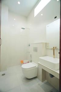 a white bathroom with a toilet and a sink at LK.Lodge in Kanyakumari