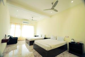 a bedroom with two beds and a ceiling fan at LK.Lodge in Kanyakumari