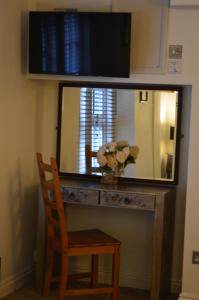 a mirror on a desk with a chair and a vase of flowers at Benson House Box in Box